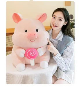 Close-up detail of a cute pink pig plush toy with lollipop accessory held by a model