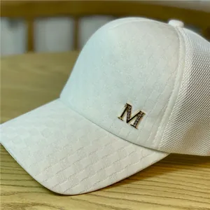 Detalle de una gorra de béisbol de malla blanca con un logotipo M brillante decorado con strass