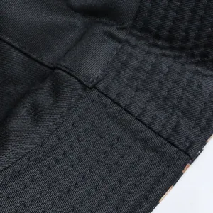 Macro view of black fabric stitching and breathable mesh on reversible bucket hat