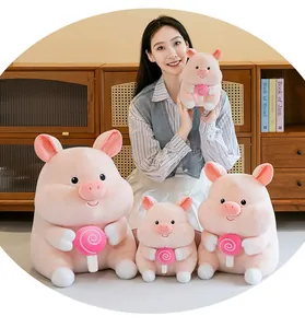 Detail shot of cute pink plush pig toys in various sizes holding a lollipop accessory