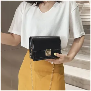 Elegant black small square crossbody bag with gold chain strap shown on a female model