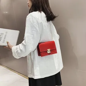 Elegant red leather crossbody bag with metal clasp and chain strap on a model