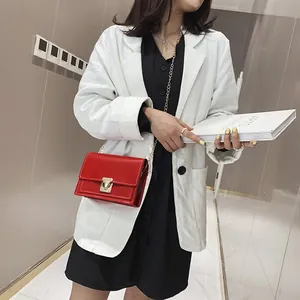 Close-up detail of a model wearing a stylish red chain square bag with a gold buckle.