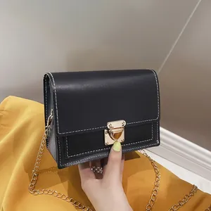 Detail view of a black square crossbody bag with contrast stitching and gold clasp