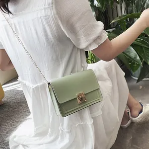Detail view of a mint green summer push-lock small square chain bag worn with a white dress