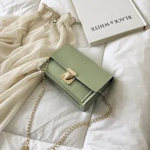 Elegant light green turn-lock small square bag with gold chain on white bedding