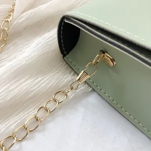 Close-up of mint green square bag with golden chain strap and stitching details