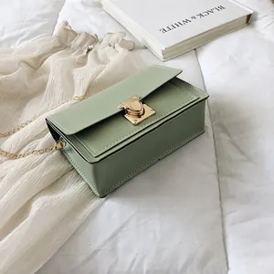 Detail of light green square crossbody bag with gold heart-shaped clasp and chain
