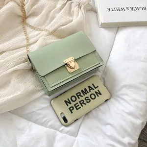 Close-up view of a stylish mint green square bag with gold chain and latch clasp