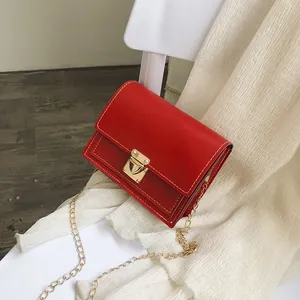 Detailed view of a trendy red small square bag with a gold latch and chain strap