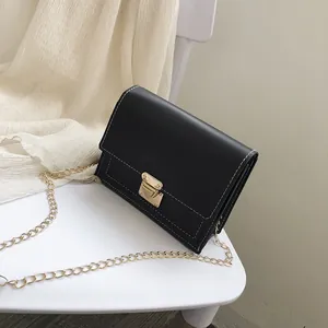 Close-up of a stylish black square crossbody bag with gold chain and flap closure