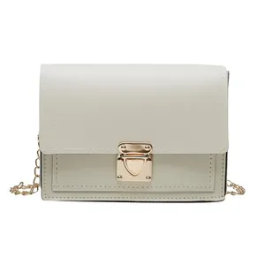 Front view detail of cream white square bag with gold hardware and a chain strap