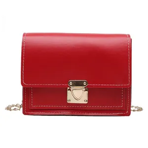 Front view of a red small square bag with a gold metal lock and white stitching.