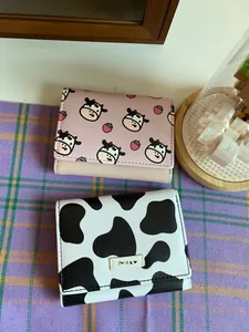 Close-up detail of cute cow pattern and strawberry print mini tri-fold wallets for women