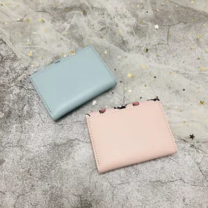 Pair of compact tri-fold wallets in pastel pink and blue with strawberry prints.