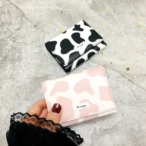 Detail view of cute cow print trifold mini wallets in black and pink fashion styles (82 chars)