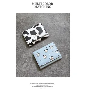 Close-up detail showing cow print and cartoon cow patterned tri-fold mini wallets.
