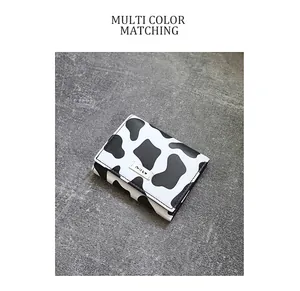 Detailed view of trifold cow print wallet with Milk label on textured background