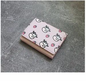 Detailed top-down view of a pink tri-fold wallet with cute cow and strawberry prints.