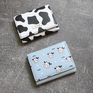 Compact trifold wallets with cute cow patterns and multi-card slots on stone background