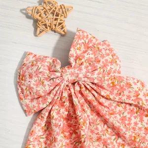 Close-up detail of a pink floral fabric bow hair clip with sweet feminine streamers
