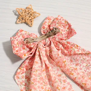 Close-up of pink floral fabric bow barrette showing metal clip and ribbon detail