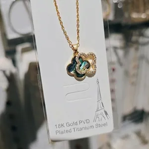 Detailed close-up of a double four-leaf clover pendant necklace in gold-plated steel