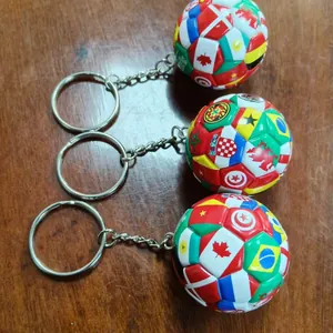 Three miniature soccer ball keychains decorated with colorful international national flags