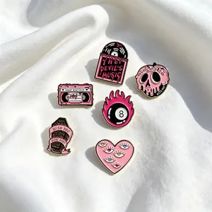 Collection of six gothic pink and black enamel pins displayed on soft white fabric