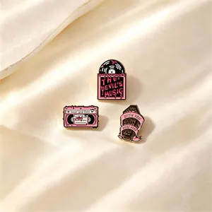 Close-up of gothic pink enamel pins featuring vinyl, cassette, and coffin designs