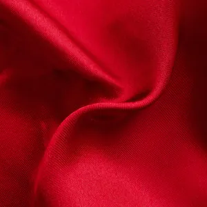 Detalle de primer plano de la textura de tela de satén rojo vibrante con brillo sedoso.