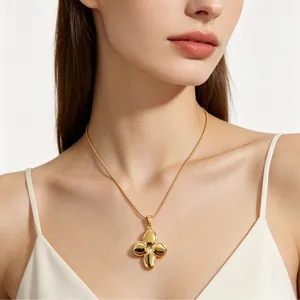 Elegant gold-toned four-leaf clover pendant necklace worn by a female model in white top