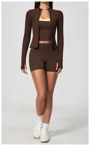 Full body shot of a woman in a brown 3-piece high-waisted yoga set with a zip-up jacket.