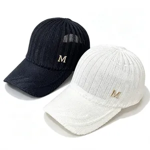 Detail view of black and white knitted baseball caps with breathable mesh and M logo.