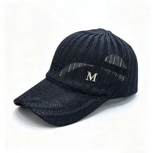 Detailed view of navy blue knitted mesh baseball cap with silver M logo emblem