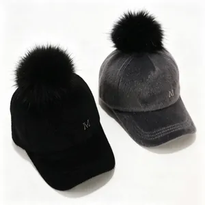 Primer plano de gorras de béisbol de invierno con pompones negros y detalle de logo M