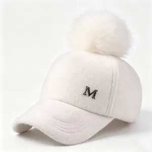 Primer plano de una gorra de béisbol de lana blanca con pompón y una insignia M de metal
