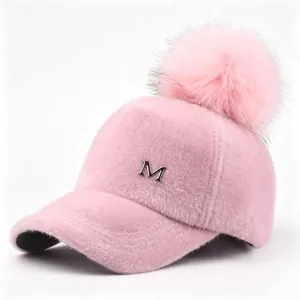 Detalle de una gorra de béisbol rosa de peluche con pompón y logotipo M