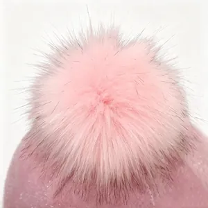 Primer plano detallado de un pompón de piel sintética rosa en una gorra de invierno