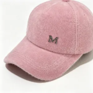 Vista macro detallada de una gorra de béisbol rosa y suave con un logo M plateado