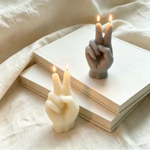 Vista dettagliata di candele profumate a forma di segno di vittoria su libri bianchi
