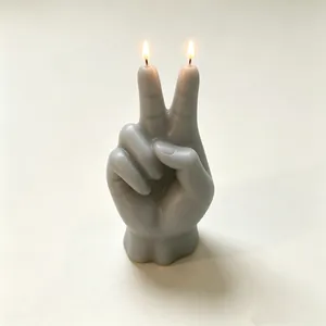 Primo piano di una candela profumata grigia accesa a forma di segno di mano della vittoria