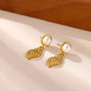 Close-up detail of gold seashell earrings with elegant white pearls on a textured background
