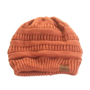 Gros plan d'un bonnet d'hiver en tricot orange pour femme avec un écusson étoilé pour le ski