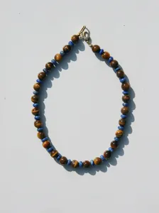 Détail d'un collier vintage en perles d'oeil de tigre avec fermoir en acier doré