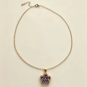 Primo piano di una collana dorata con pendente a fiore in cristallo viola vibrante