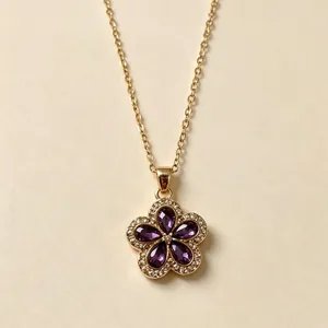 Vista dettagliata di una collana in oro con ciondolo a fiore di cristallo viola a 5 petali