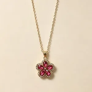 Primo piano di una collana a fiore dorata con cristalli rosa e dettagli micro-pavé.