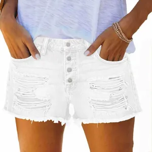 Close-up of white high-waisted ripped denim shorts with button fly and frayed hem