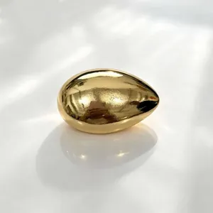 Close-up view of a minimalist smooth metallic gold egg-shaped vintage fashion brooch